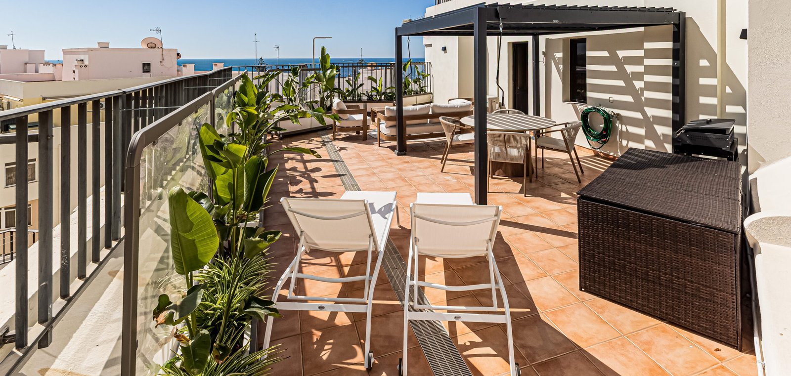 Spacious 84 m² private rooftop terrace with pergola, outdoor dining area, sun loungers and panoramic sea views at Paraíso de Pêra in Armação de Pêra, Algarve.